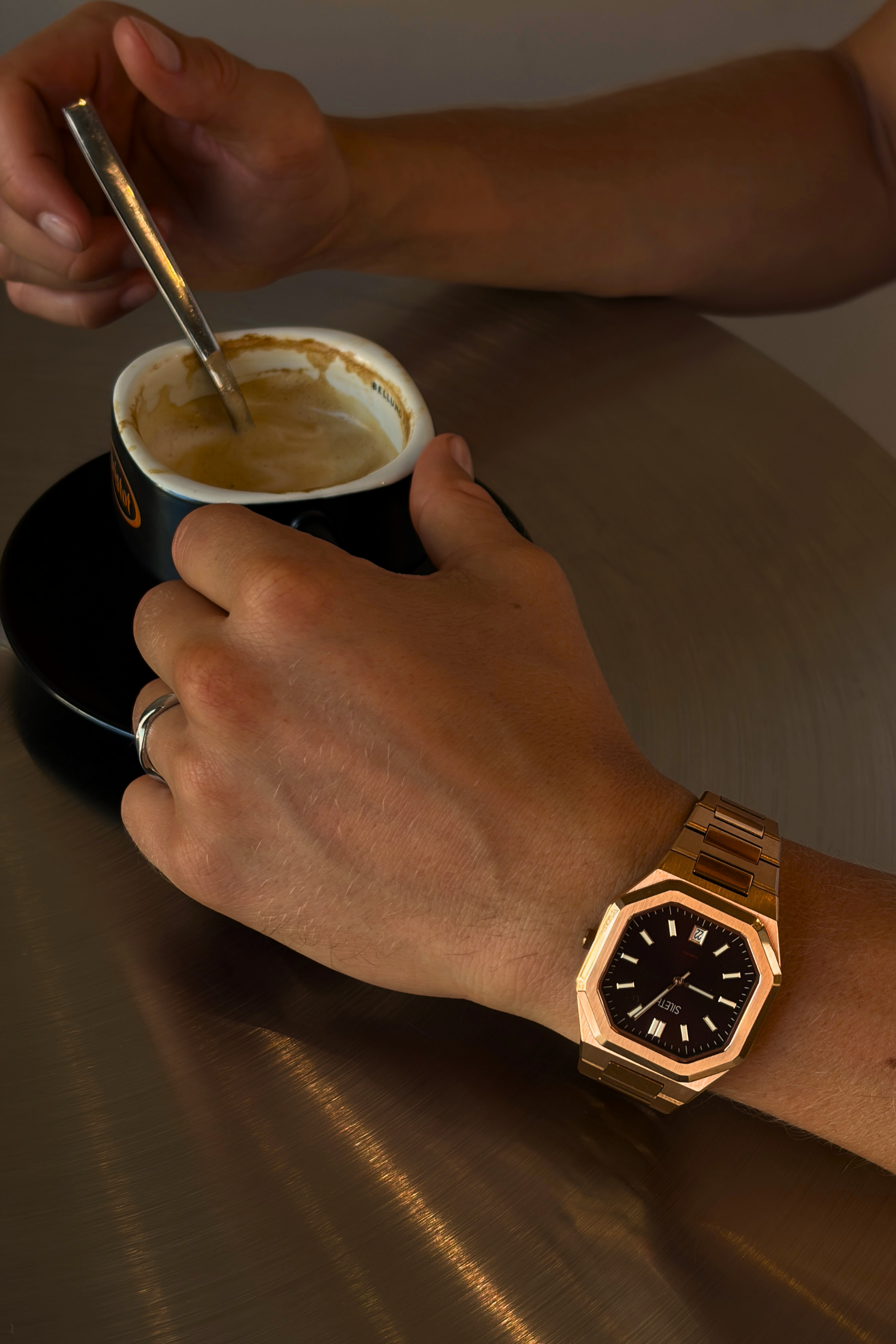 VARENNA Tobacco Heritage rose gold watch on the wrist while holding a cappuccino in a cafe